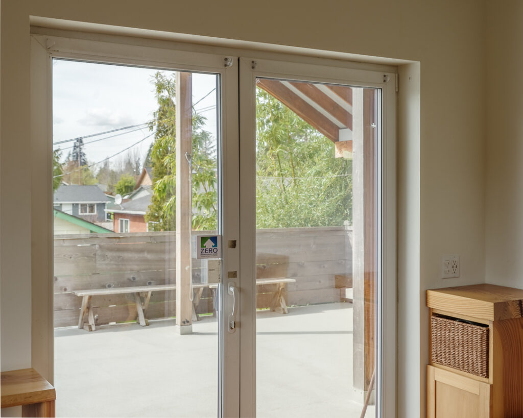 A close-up photo of the entry french doors looking out onto the entry patio. There is a sticker with the Net Zero Energy Ready certification logo and it says "Zero".