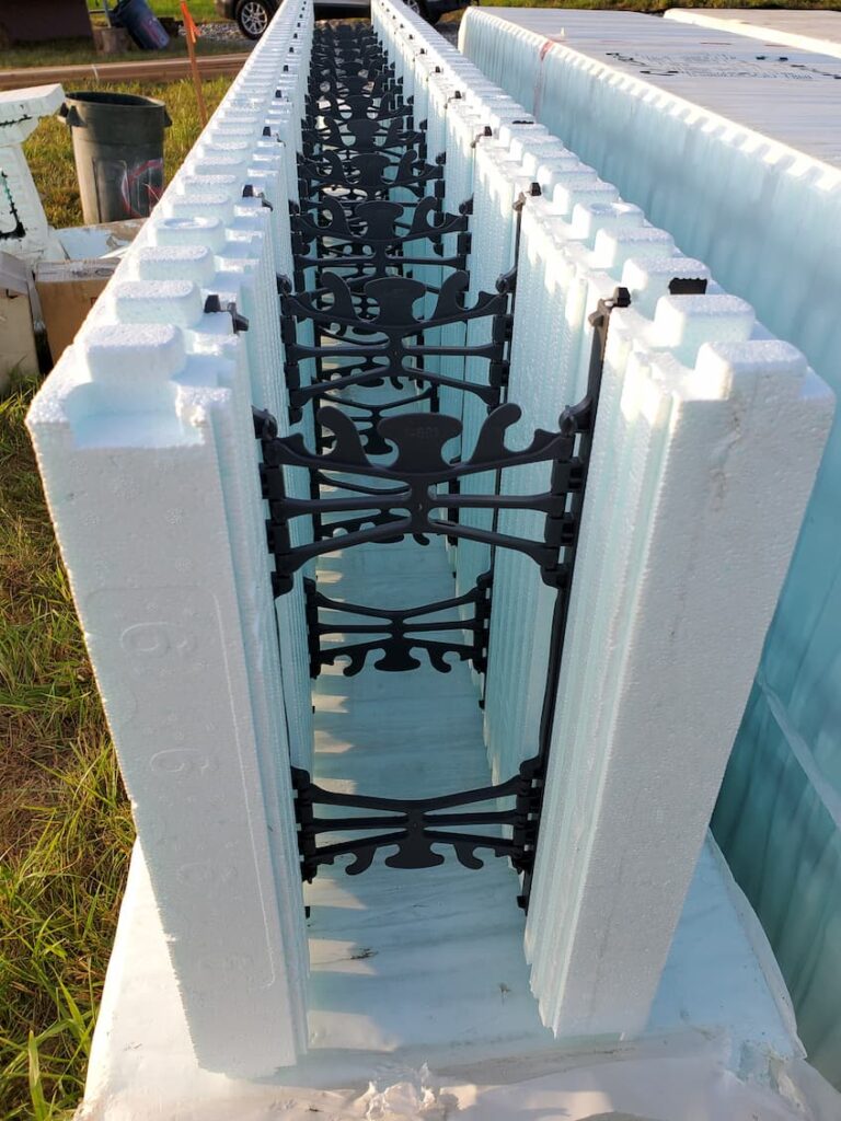 A close-up photo of an insulated concrete form (ICF) block, which is a few inches thick foam sandwiching a thin plastic skeleton to hold the two sides of foam together. The concrete gets poured in between the foam over the plastic skeleton. 