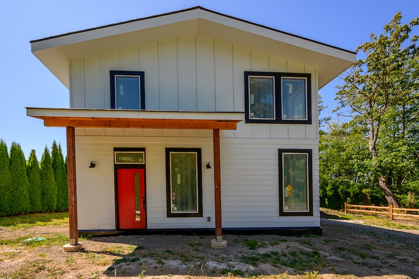 Point Whitehorn net-zero home was featured in The Northern Light. 
A photo of the front exterior of a white home with red door and black trim.